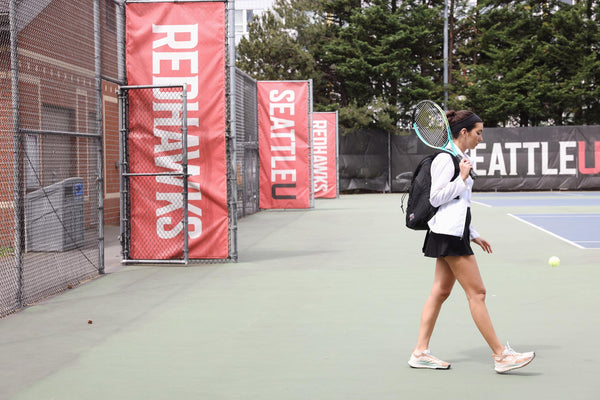 A person carrying a Smart Alec 2.0 holding a tennis racquet.